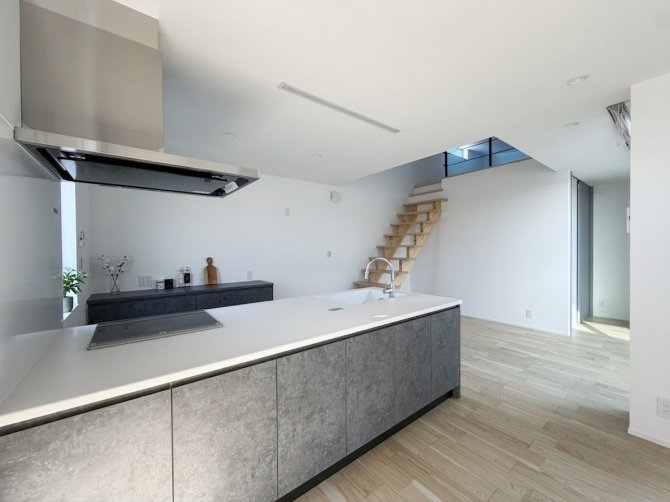 白のクロスでまとめた空間に、グレーのキッチンが映える落ち着いたLDK。立ち上がり壁のないフラットキッチンはデザイン性が高く、視線が抜けることで空間に広がりと開放感をもたらします。