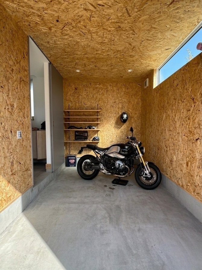 趣味を思いきり楽しめるこだわりのガレージ。OSB合板のラフな質感とコンパクトな空間が「大人の秘密基地」です。ガレージから玄関へ直接アクセスできる動線で、雨の日でも濡れずに出入りできます。