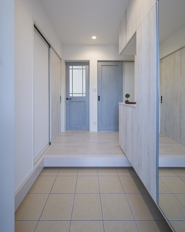やさしいブルーの建具が印象的な玄関ホール。玄関収納は空間に馴染む色味でまとめ、すっきりとした印象に。シンプルな中に色使いの工夫を取り入れ、毎日の出入りが心地よくなる玄関に仕上げました。