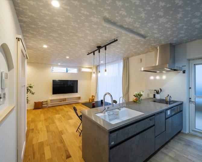 遊び心ある天井クロスが空間にアクセスを加え、グレーのキッチンが上品で落ち着いた印象を与えます。
木目の床とのバランスも良く、自然光がたっぷり差し込む明るく心地よいLDKに仕上がりました。