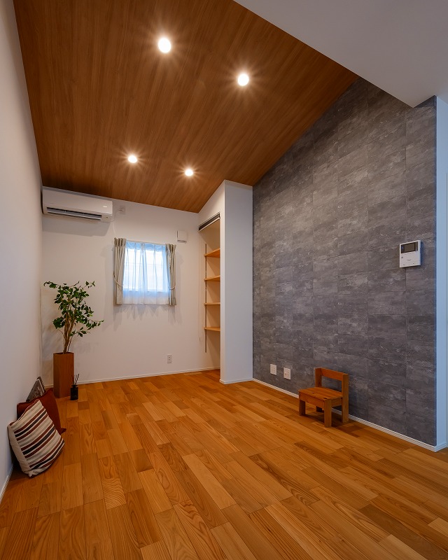 木目の片流れ天井が空間に広がりをもたらし、スタイリッシュなグレーのアクセントクロスが空間にメリハリを与えます。