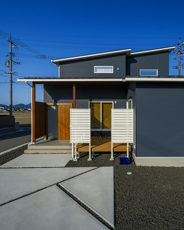ネイビーの外壁に木目と白のアクセントが映える、スタイリッシュな外観デザイン。
視線を遮る目隠しフェンス付きのウッドデッキは、プライベートを確保しながら屋外空間を楽しめます。
片流れ屋根のラインがモダンな印象を与え、街並みにも映える佇まいです。