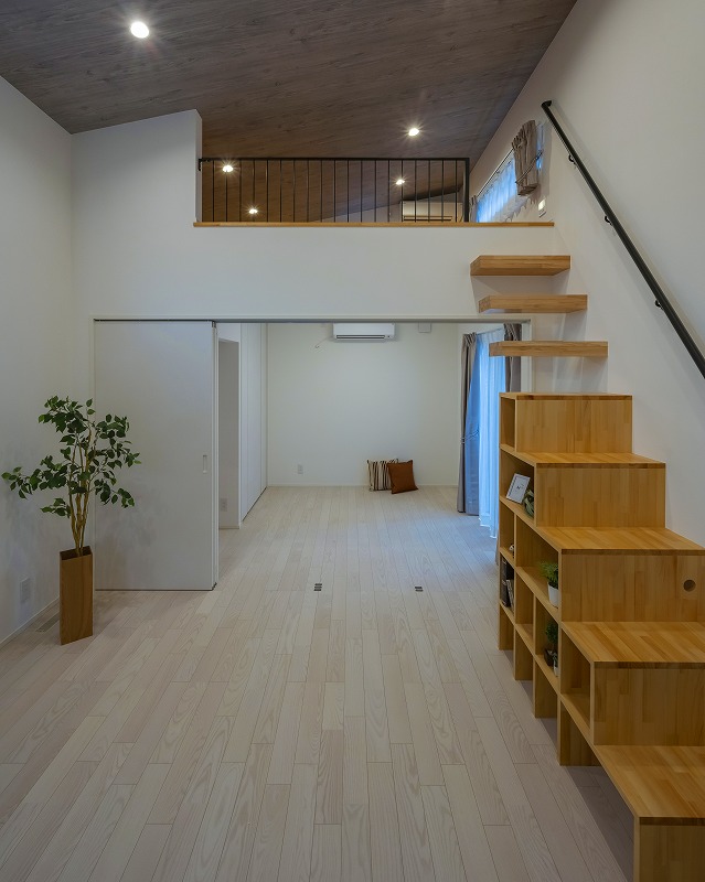 白を基調とした明るく開放的なLDKは、吹き抜けによって上下階がゆるやかにつながります。収納力のある箱階段と、軽やかなデザインの持出階段を組み合わせた造作階段は、実用性とデザイン性を両立しています。