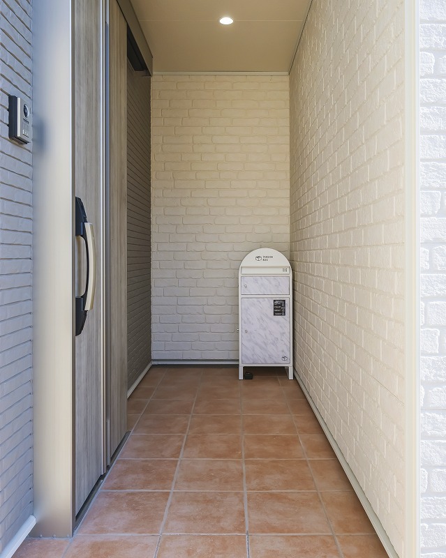 壁で囲まれた玄関ポーチは、外からの視線を遮り安心して過ごせる空間に。宅配ボックスを置ける十分な広さを確保し、雨や風を気にせず荷物を受け取れる安心設計。暮らしを支える実用性と住まいに馴染むデザイン性を両立した玄関空間です。