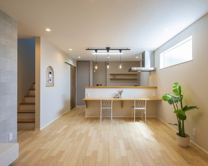 ナチュラルな木目調フローリングと明るい白のクロスが調和した、清潔感あふれるLDK。
キッチンカウンターはデスクのように使える設計で、食事だけでなくワークスペースや子どもの学習場所としても活躍します。
背面の飾り棚は見せる収納として、植物や小物を飾ることでカフェ風のインテリアを楽しむことができます(^^♪