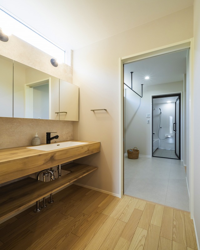 木の質感を活かした造作洗面台。
横長の大きなミラーキャビネットは収納力もあり、空間を広く見せる効果があります。
洗面から脱衣所、浴室へとつながるスムーズな動線は、毎日の家事や身支度を快適にサポートしてくれます。