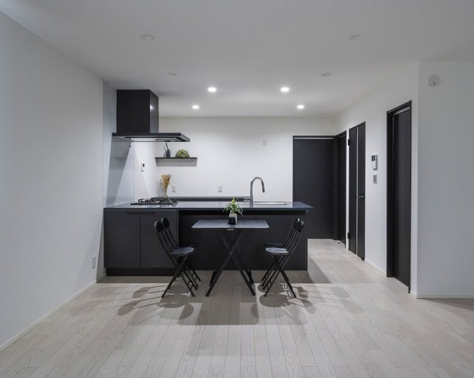 モノトーンで統一されたキッチンは、落ち着いた大人のかっこよさを漂わせます。ブラックのカウンターと扉が白い壁や明るい床に映え、空間全体をスタイリッシュに引き立てます。無駄のないレイアウトと広がりのあるカウンターが、快適で効率的な作業を叶えてくれます。