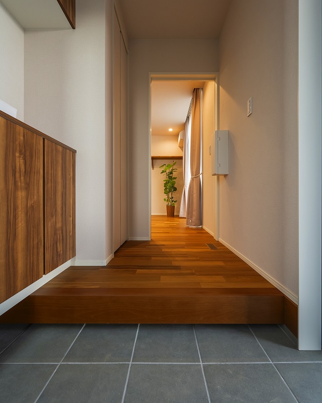 木目調の玄関収納とフローリングが統一感を生み、奥まで視線が抜ける動線計画。
また、奥の部屋から届く自然光が玄関を明るく仕上げています。