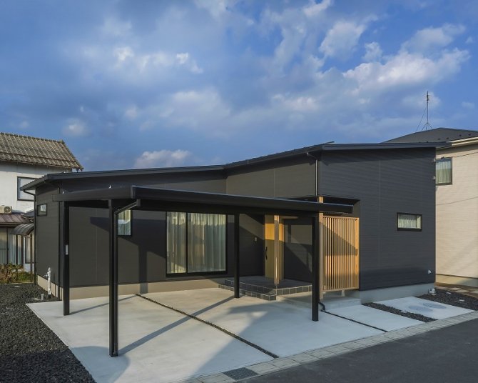 片流れ屋根の形を活かしたスッキリとした外観。
玄関まわりには格子を設け、光や風を取り込みながらも外からの視線をコントロール。カーポートを含めた外構までトータルで計画し、日常の動線に配慮しながら外観の一体感を高めました。